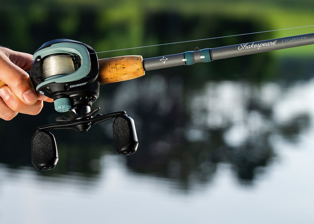 Fishing rod with reel held by a hand, blurred natural background